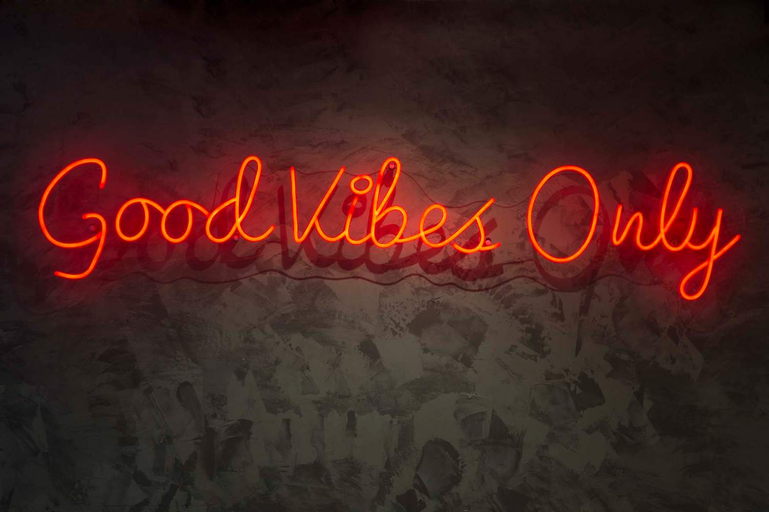 Neon with the word good vibes only, on wall texture.